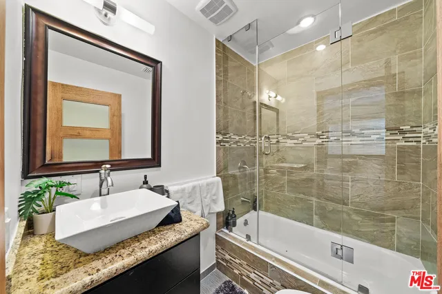 a bathroom with a granite countertop tub sink and mirror