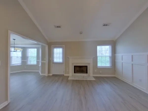 an empty room with wooden floor fireplace and windows