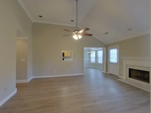 a view of an empty room with window and wooden floor