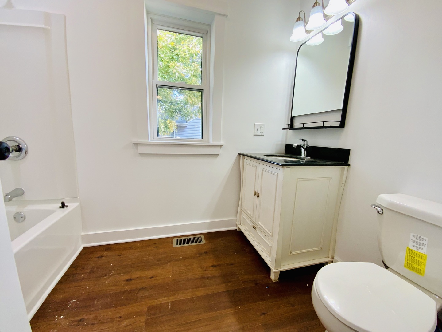1002 Adams Street Ottawa, IL 61350 - Photo 13 of 14 a bathroom with a toilet a sink a mirror a window and wooden floor