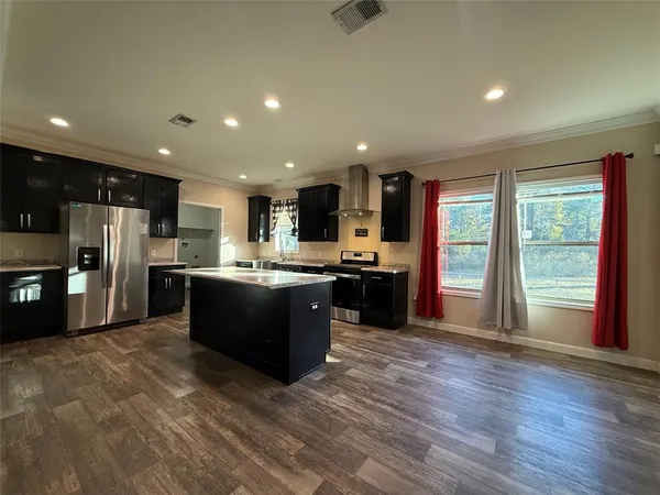 a large kitchen with stainless steel appliances granite countertop a large counter top a refrigerator and a sink