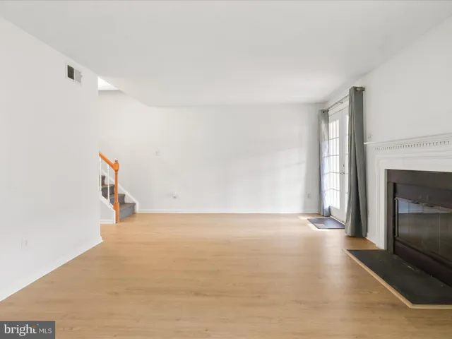 a view of empty room with wooden floor and fireplace