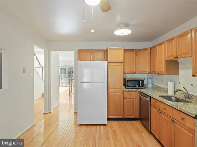 a kitchen with a refrigerator a sink and dishwasher with wooden floor