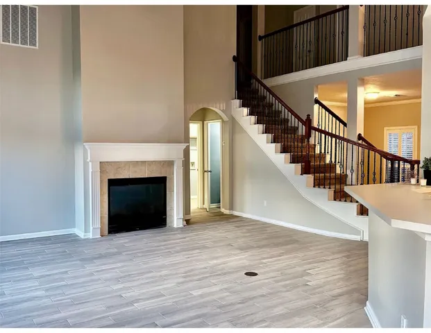 a view of an empty room with wooden floor and a fireplace