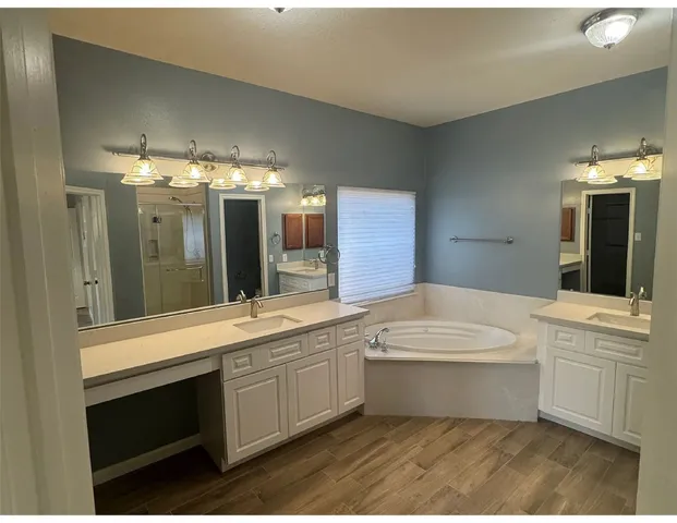 a large bathroom with a large tub sink vanity and granite