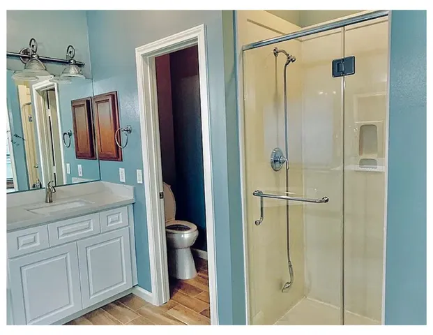 a bathroom with a granite countertop sink a mirror a vanity and a shower