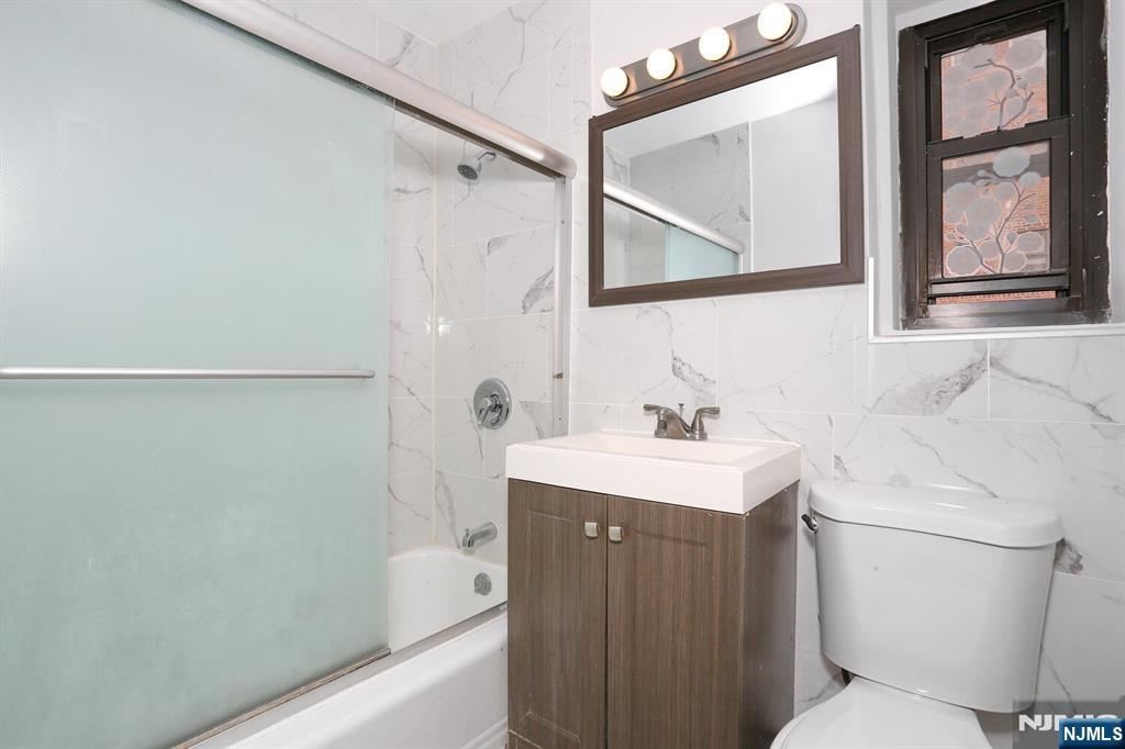 208 Anderson Street, Unit S4F Hackensack, NJ 07601 - Photo 13 of 18 a bathroom with a sink a toilet and a mirror