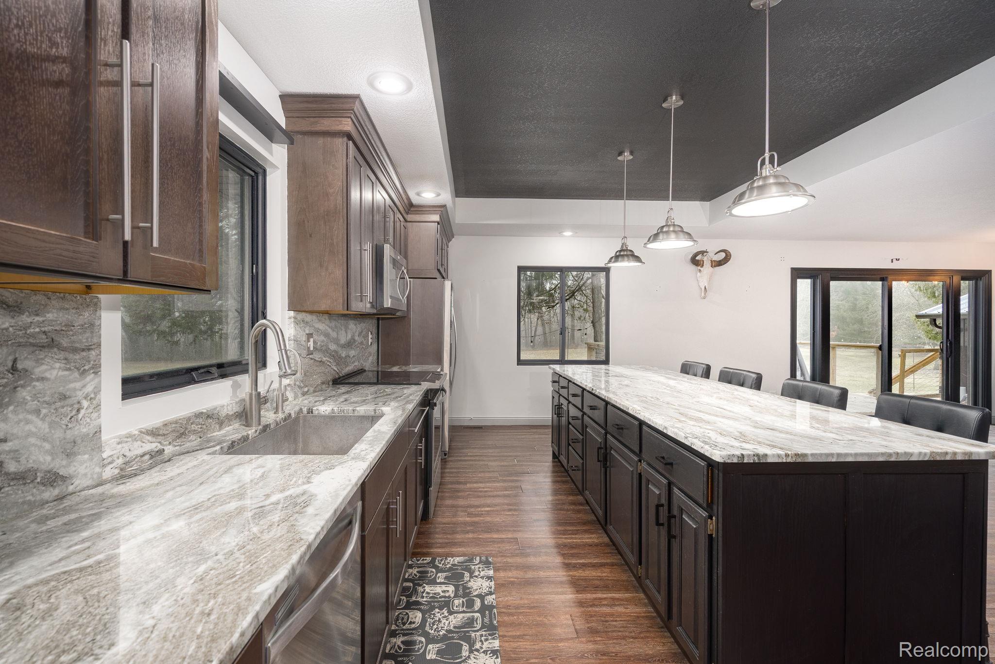 6803 Napoleon Road Jackson, MI 49201 - Photo 22 of 59 Kitchen featuring dark wood finish cabinetry, light stone counters, a kitchen island, and a raised ceiling
