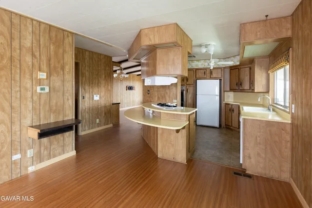 a kitchen with stainless steel appliances a refrigerator a sink dishwasher and wooden cabinets with wooden floor