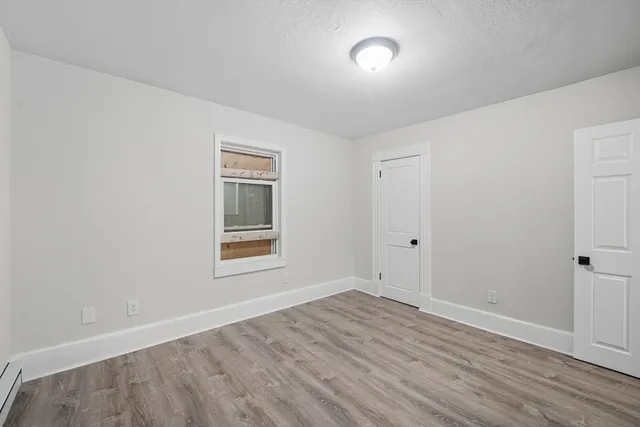 a view of an empty room with wooden floor and a window