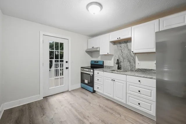 a kitchen with granite countertop a stove a sink and a refrigerator