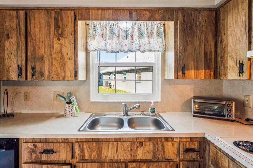 6709 Timbercove Lane, Unit 6709 New Port Richey, FL 34653 - Photo 12 of 52 a kitchen with wooden cabinets a sink and a window