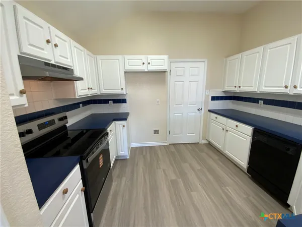 a kitchen with granite countertop a stove sink and cabinets