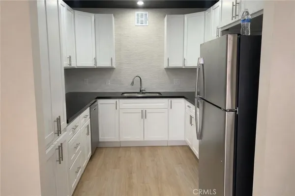 a kitchen with white cabinets and refrigerator