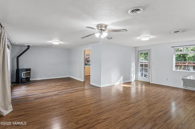 a view of empty room with wooden floor and fan