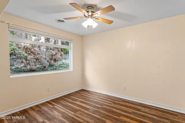 a view of a big room with wooden floor and a chandelier fan