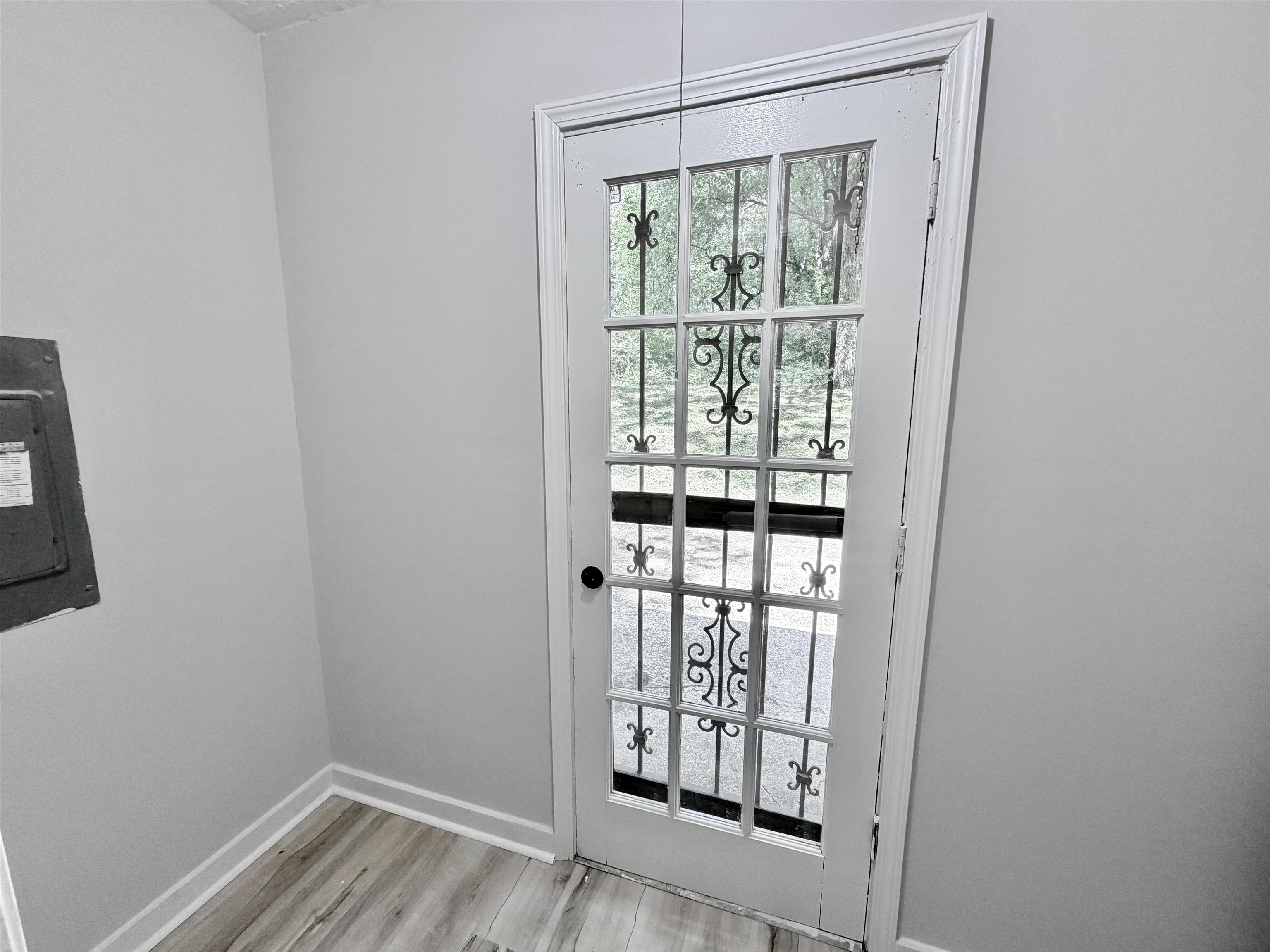 4278 Auburn Road Memphis, TN 38116 - Photo 25 of 28 White framed glass-panel door with decorative iron inserts, wood-finish flooring, white baseboards, and light gray wall paint
