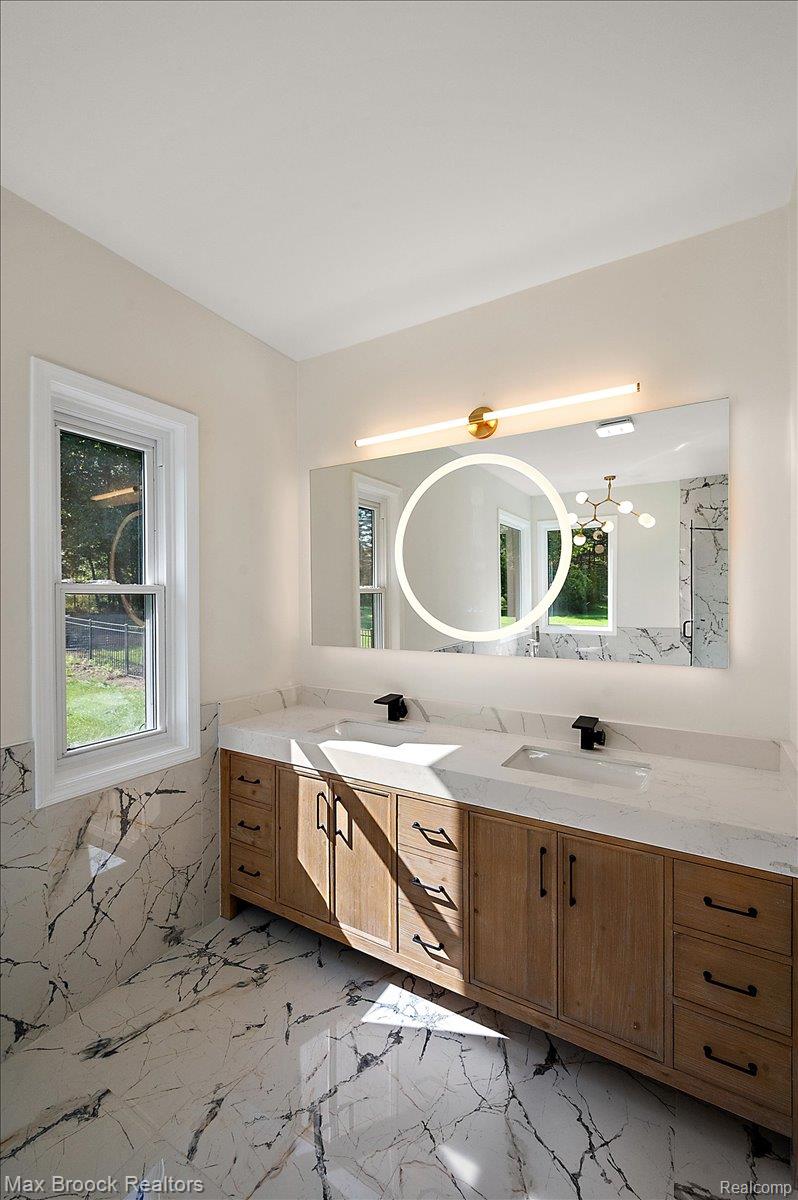 4597 Clarkston Road Clarkston, MI 48348 - Photo 32 of 74 Dual vanity with integrated sinks and black fixtures, framed by a large illuminated mirror