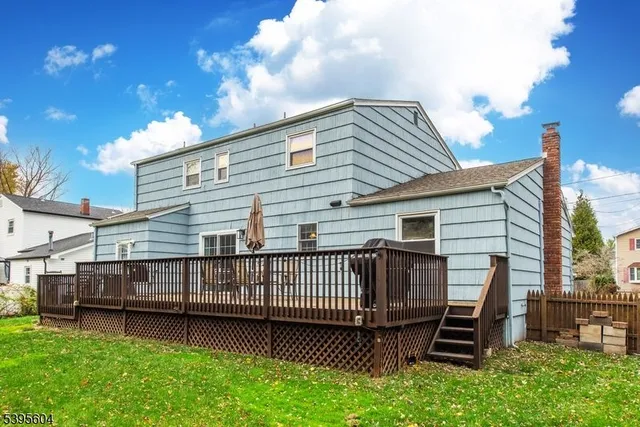 a view of a house with a wooden deck and a yard