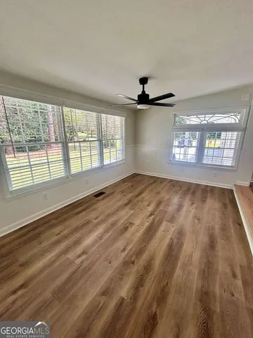 an empty room with wooden floor and windows