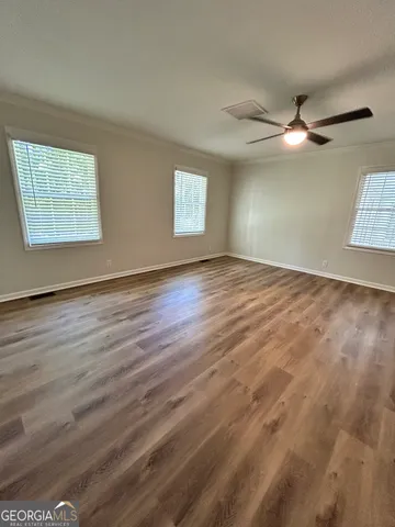 a view of an empty room with window and wooden floor