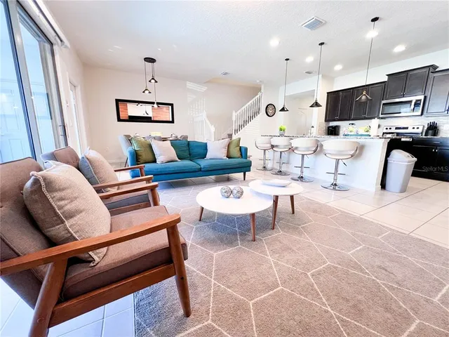 a living room with furniture kitchen view and a wooden floor
