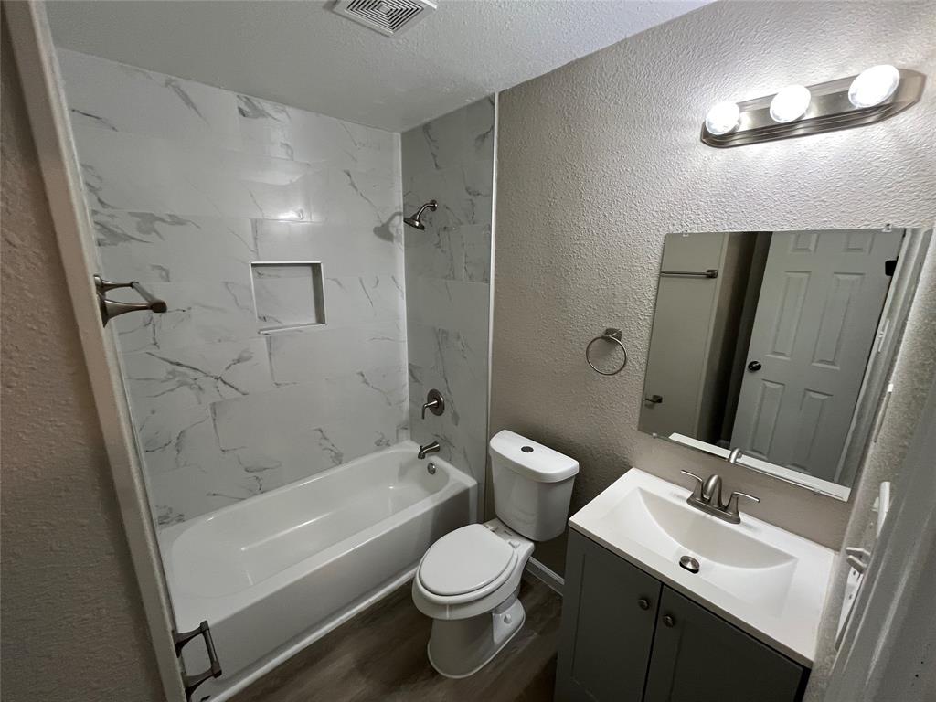 7642 Maxwell Avenue Dallas, TX 75217 - Photo 11 of 20 Full bathroom featuring a textured wall, vanity, shower / tub combination, dark wood-type flooring, and a textured ceiling