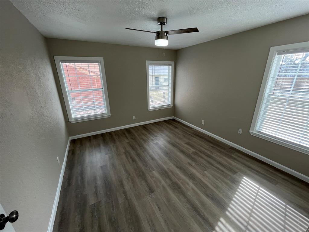 7642 Maxwell Avenue Dallas, TX 75217 - Photo 13 of 20 Unfurnished room with a textured ceiling, dark wood-style floors, and ceiling fan
