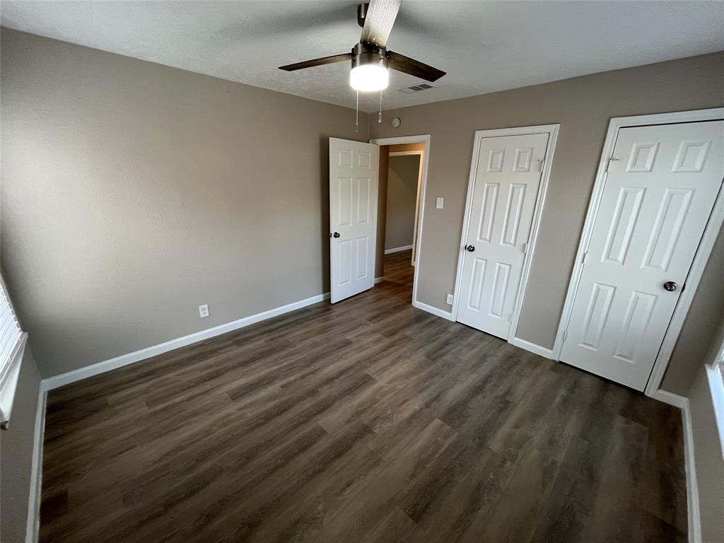 7642 Maxwell Avenue Dallas, TX 75217 - Photo 16 of 20 Unfurnished bedroom featuring two closets, a ceiling fan, and dark wood-type flooring
