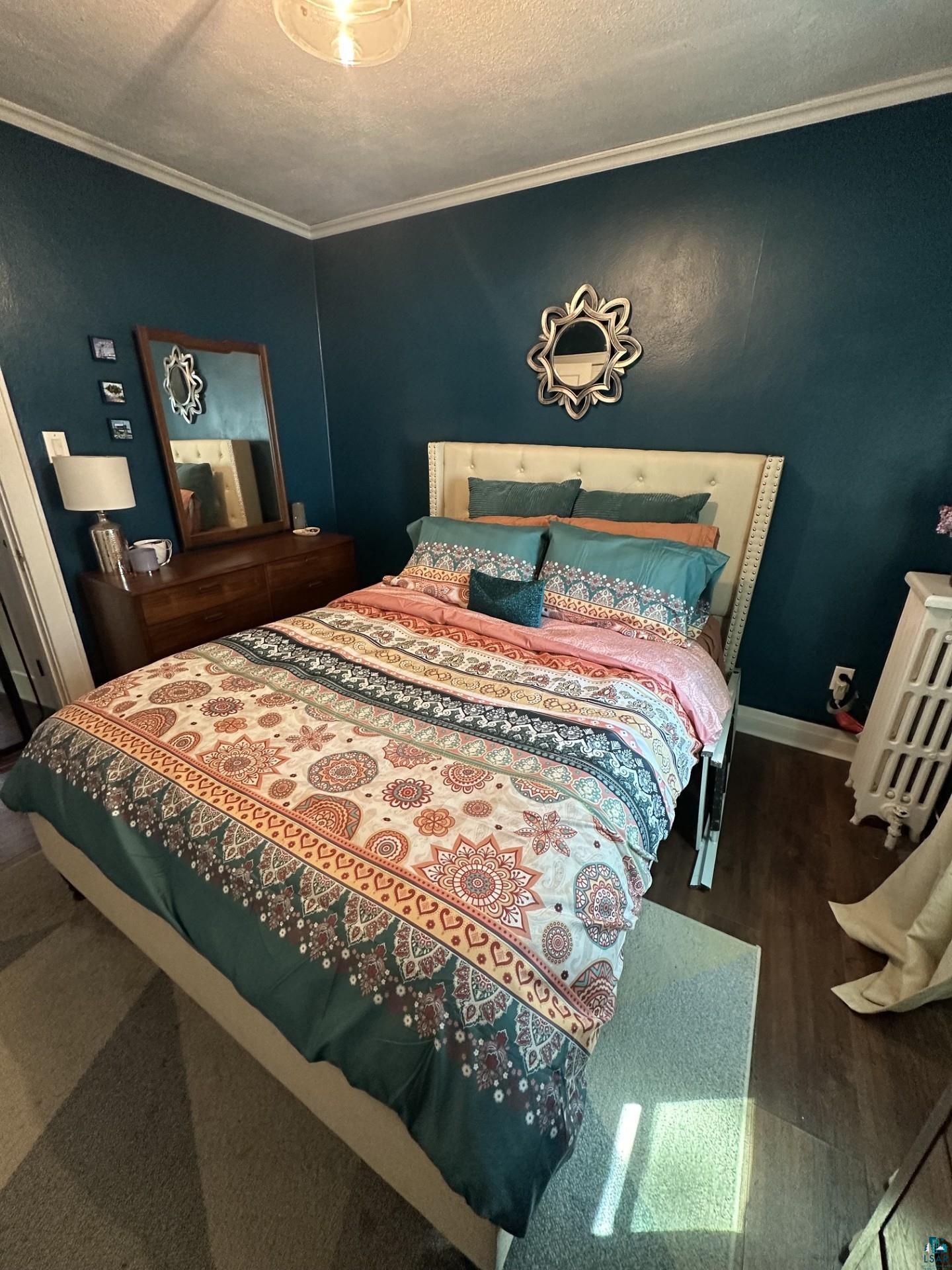 208 Chestnut Street Cloquet, MN 55720 - Photo 17 of 24 Room featuring deep teal walls with white crown molding, wood-finish flooring, and a contemporary ceiling light fixture