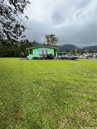 a view of a big house with a big yard and large trees