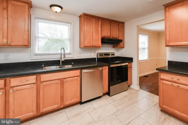 a kitchen with stainless steel appliances granite countertop a stove a sink and a white cabinets