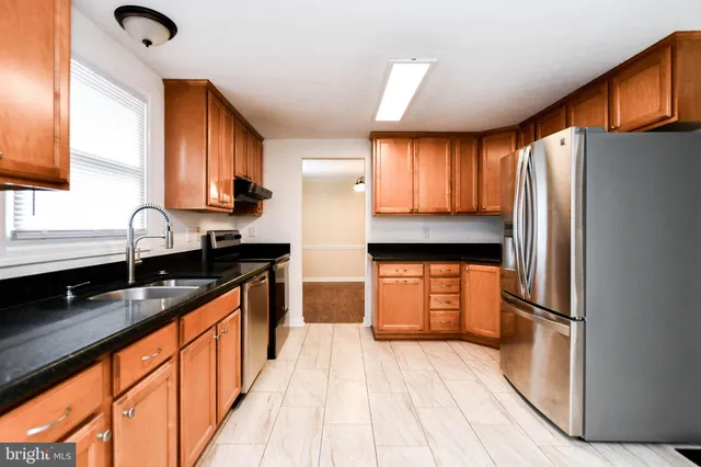 a kitchen with granite countertop stainless steel appliances a refrigerator and a sink