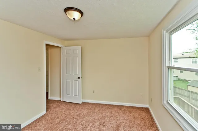 a view of an empty room with window and closet area