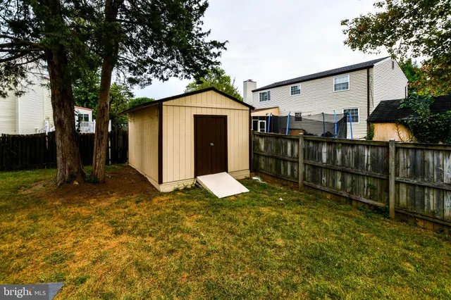 a view of a small yard in front of a house with large tree and wooden fence