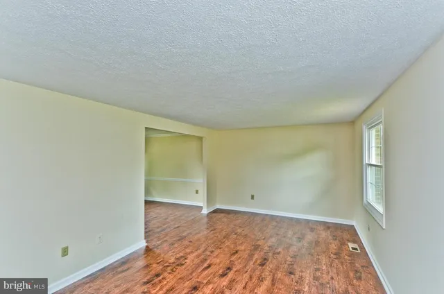 an empty room with wooden floor and window