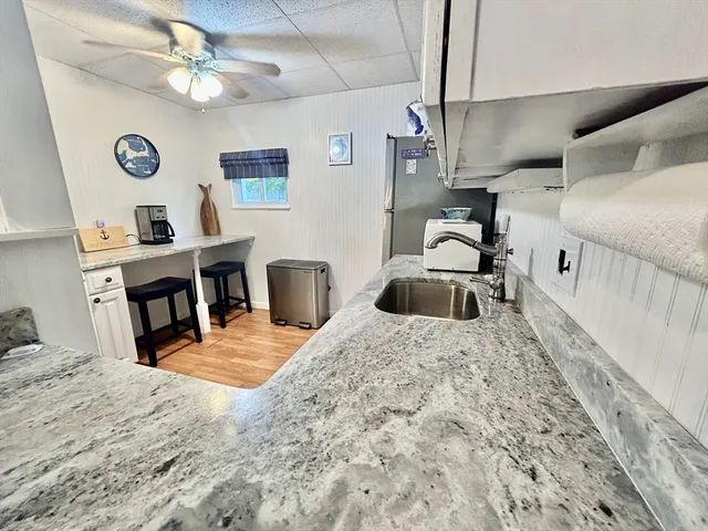 a kitchen with stainless steel appliances kitchen island granite countertop a sink a stove top oven a chimney and a refrigerator