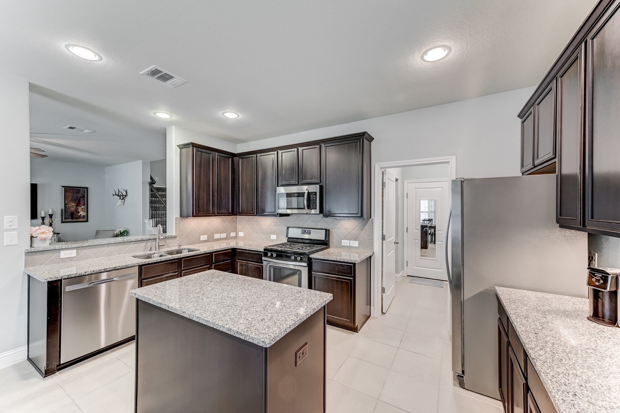 23831 Pennington Hills Drive Spring, TX 77389 - Photo 17 of 46 a kitchen with stainless steel appliances granite countertop a sink stove microwave and refrigerator