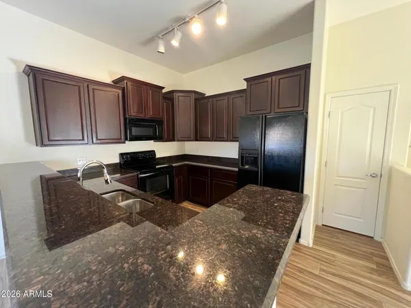 a kitchen with kitchen island granite countertop wooden cabinets a refrigerator and a sink