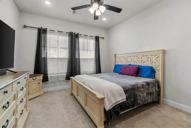 a bedroom with a large bed and a flat tv screen on dresser