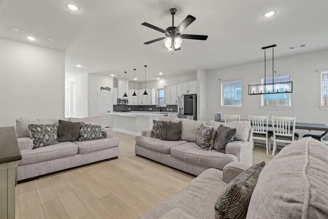 a living room with furniture kitchen view and a chandelier