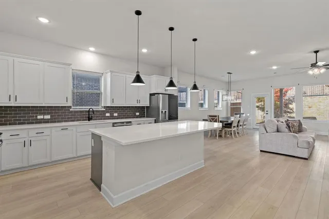 a large kitchen with kitchen island a white cabinets and couches