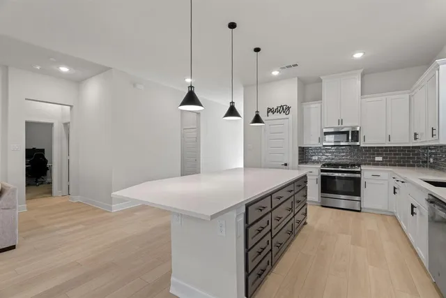 a kitchen with stainless steel appliances kitchen island a large stove a sink dishwasher and a refrigerator