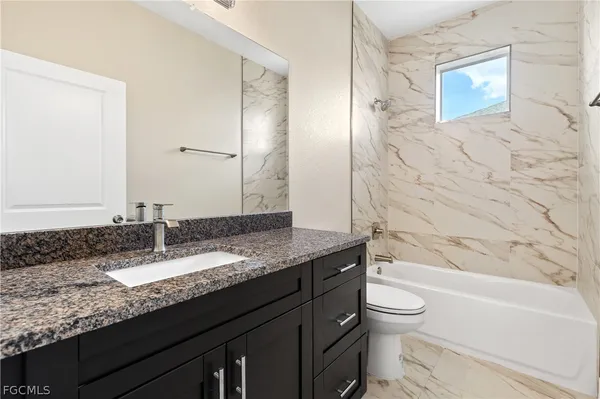 a bathroom with a granite countertop sink a toilet and bathtub