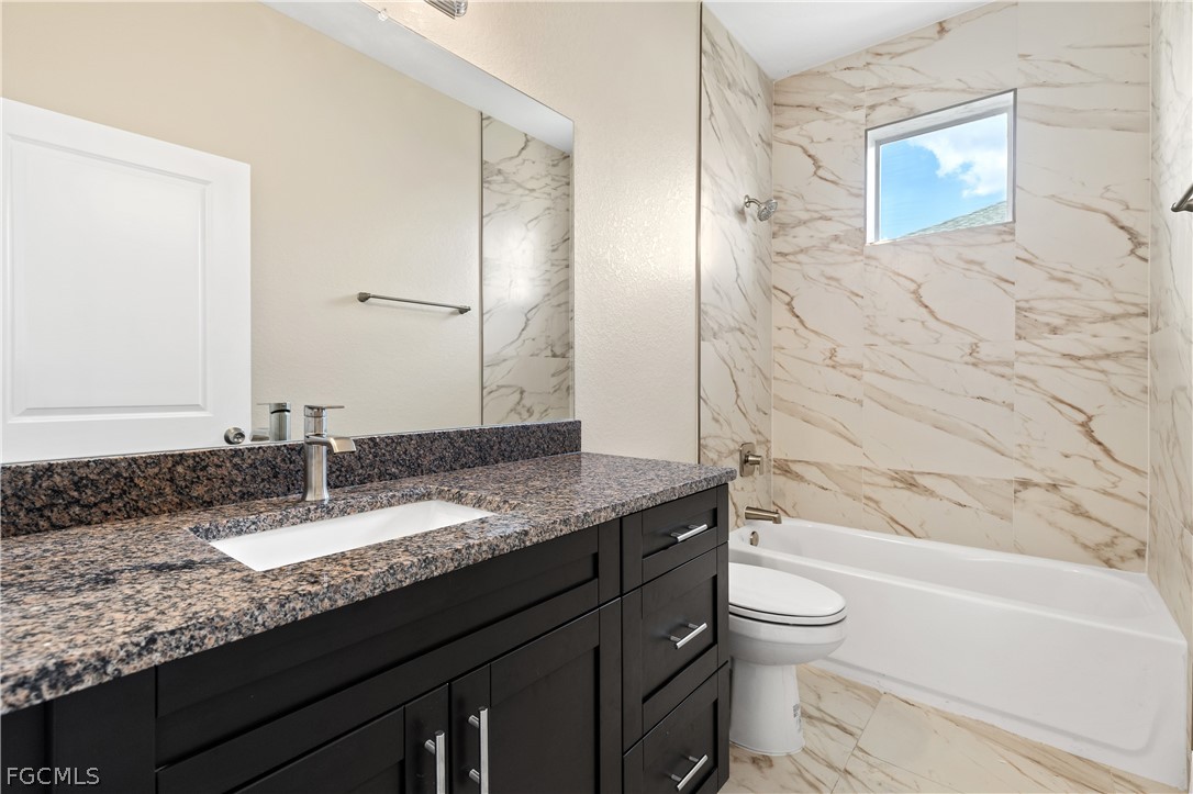 2919 23rd Street Southwest Lehigh Acres, FL 33976 - Photo 12 of 17 a bathroom with a granite countertop sink a toilet and bathtub
