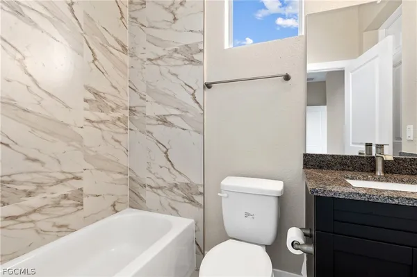 a bathroom with a granite countertop toilet sink and mirror