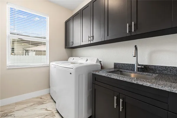 a utility room with granite countertop cabinets washer and dryer