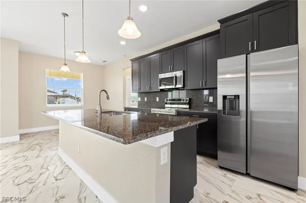 a kitchen with stainless steel appliances granite countertop a sink a refrigerator and a granite counter tops