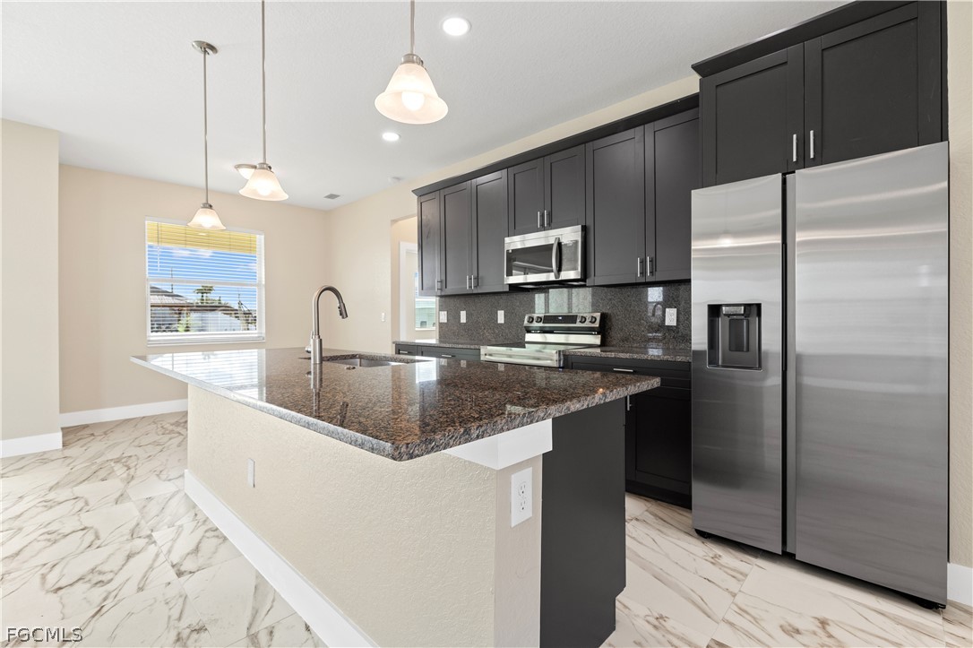 2919 23rd Street Southwest Lehigh Acres, FL 33976 - Photo 5 of 17 a kitchen with stainless steel appliances granite countertop a sink a refrigerator and a granite counter tops