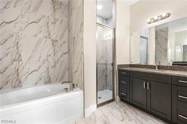 a bathroom with a granite countertop sink and a bathtub